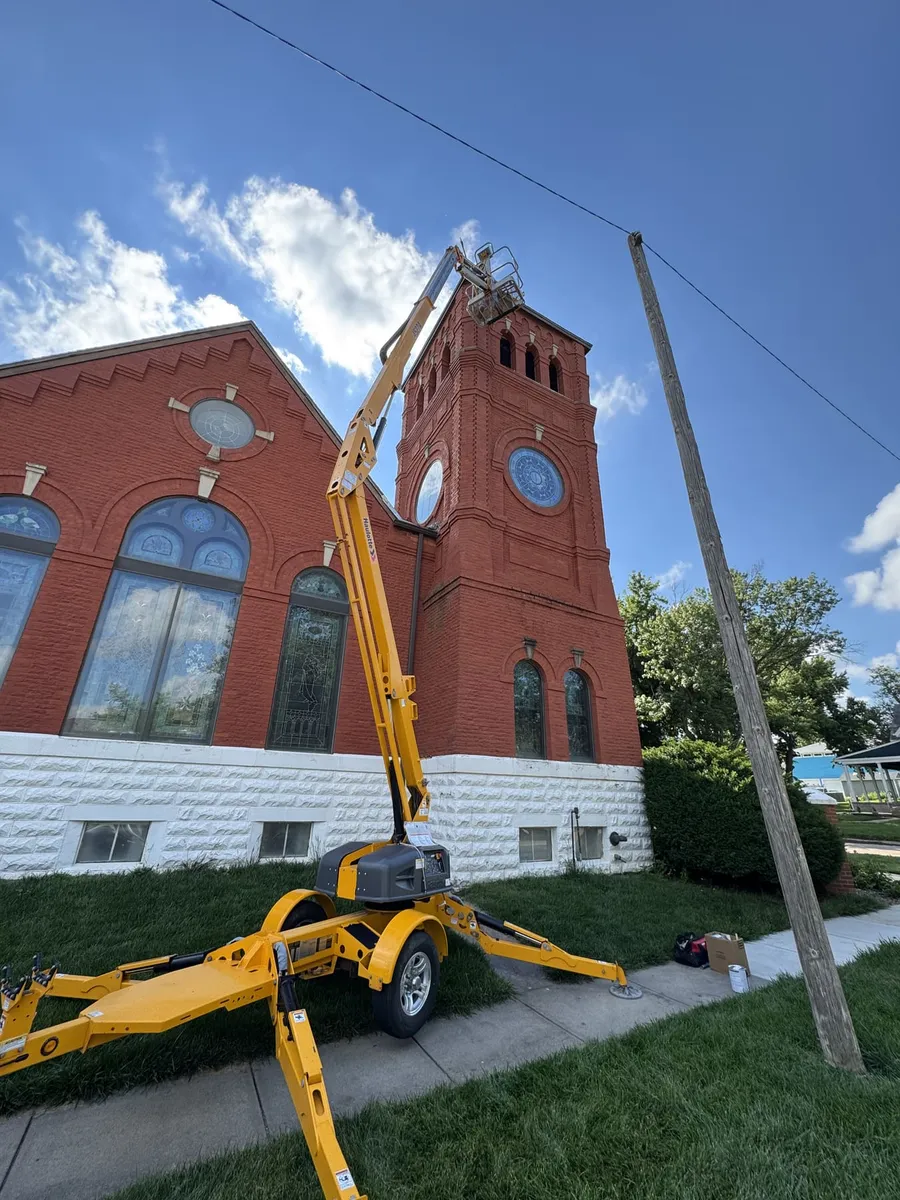G.W. Painting's boom lift raised to the bell tower of a historic Nebraska brick church
